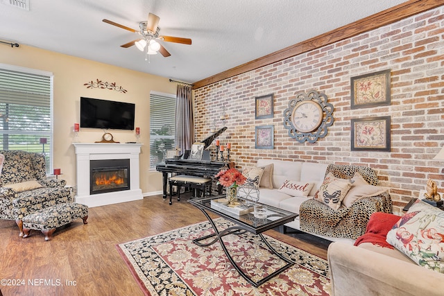 living room with ceiling fan, hardwood / wood-style flooring, brick wall, and a textured ceiling