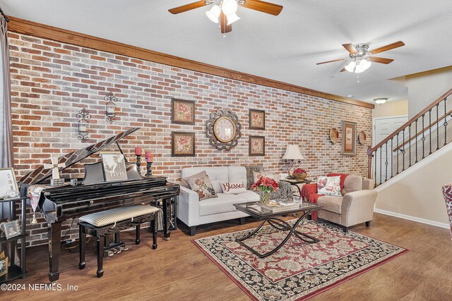 living room with ceiling fan, brick wall, a textured ceiling, and hardwood / wood-style floors