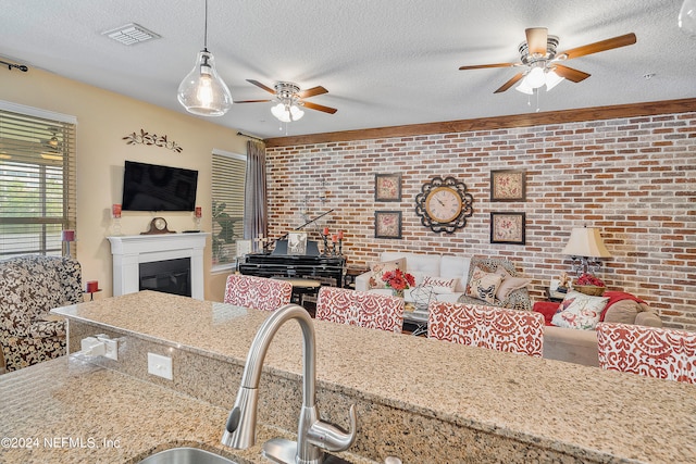 living room featuring brick wall, a textured ceiling, sink, and ceiling fan