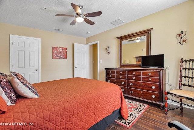 bedroom with a textured ceiling, dark hardwood / wood-style flooring, and ceiling fan