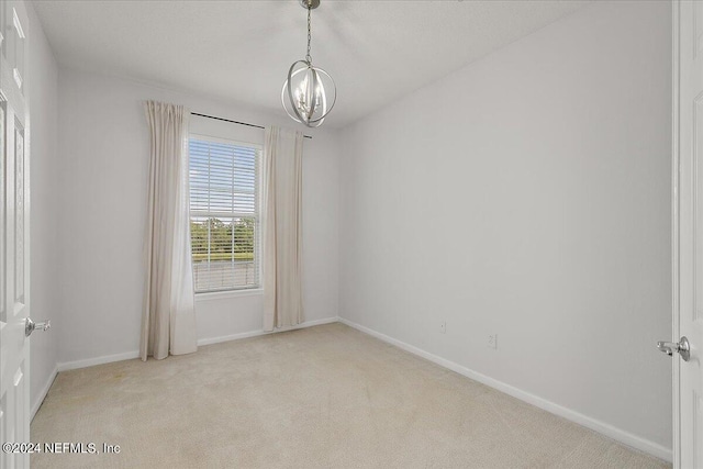 carpeted empty room featuring a notable chandelier