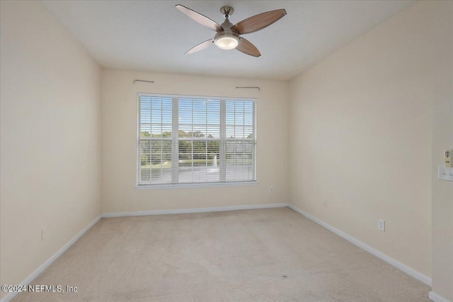 spare room with light colored carpet and ceiling fan