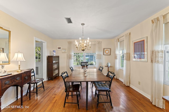 dining area with wood-type flooring, a chandelier, and a healthy amount of sunlight