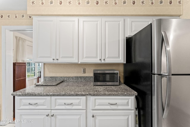 kitchen featuring stainless steel appliances, stone countertops, and white cabinetry