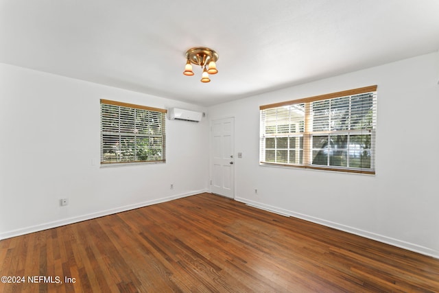 spare room featuring an AC wall unit, plenty of natural light, and hardwood / wood-style floors