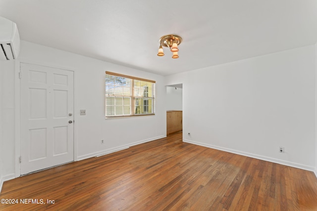 spare room featuring dark hardwood / wood-style flooring and a wall unit AC