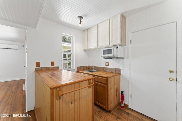 kitchen with sink, a wall mounted AC, hardwood / wood-style floors, and butcher block counters