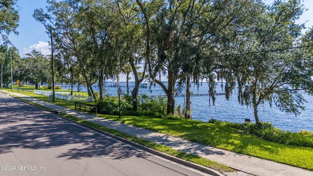 surrounding community with a water view and a lawn