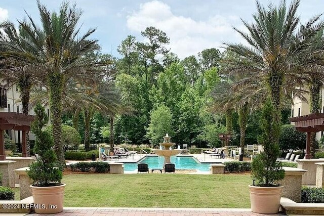 view of community featuring a pergola, a pool, and a lawn