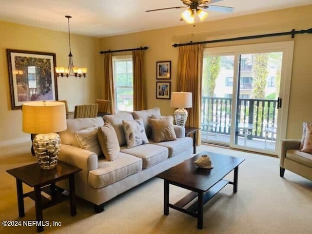 living room featuring carpet floors, ceiling fan with notable chandelier, and plenty of natural light