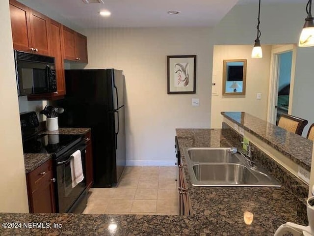 kitchen featuring hanging light fixtures, light tile patterned floors, sink, black appliances, and a breakfast bar