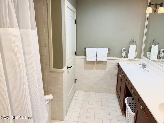 bathroom featuring walk in shower, vanity, tile walls, and tile patterned floors