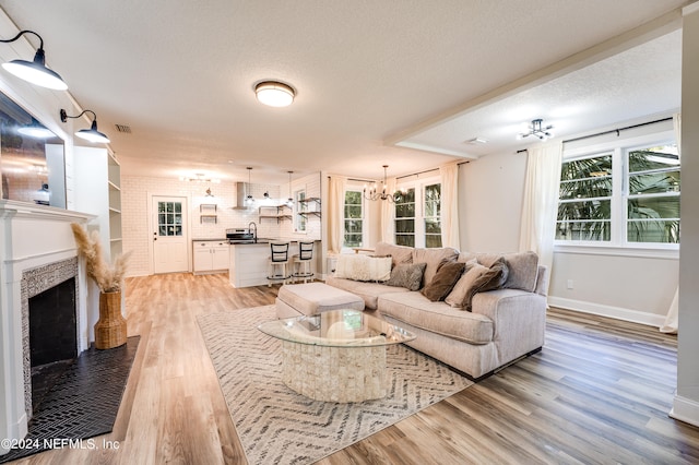 living room with light hardwood / wood-style flooring, a wealth of natural light, a textured ceiling, and sink