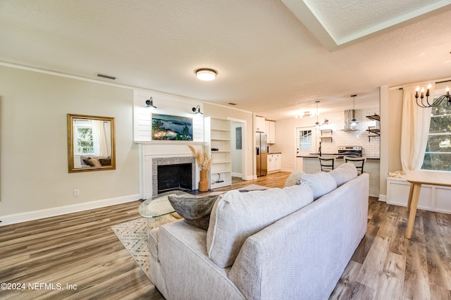 living room with a healthy amount of sunlight, hardwood / wood-style floors, brick wall, and a notable chandelier