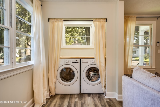 clothes washing area featuring washer and dryer, dark hardwood / wood-style flooring, and a healthy amount of sunlight