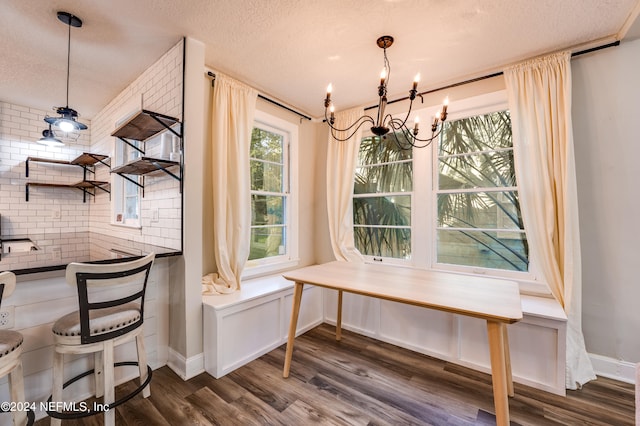 dining room with an inviting chandelier, a textured ceiling, and dark hardwood / wood-style flooring