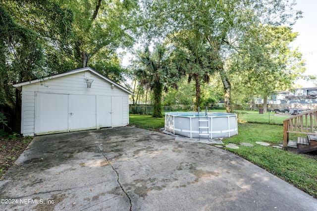 garage featuring a fenced in pool and a lawn