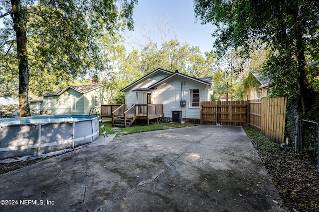 back of house featuring cooling unit and a swimming pool side deck