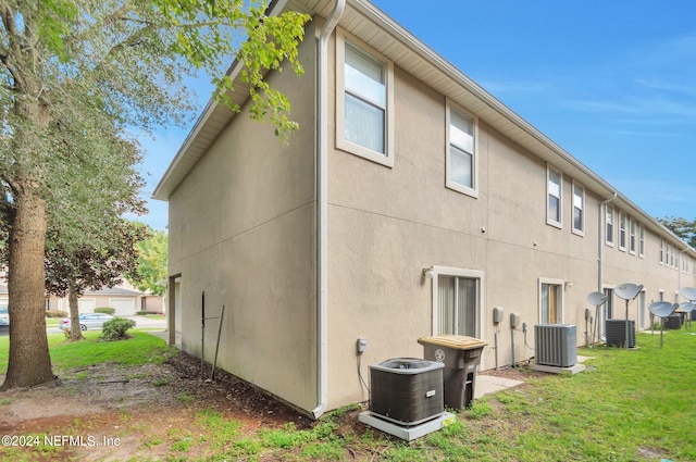 rear view of property with a lawn and central air condition unit