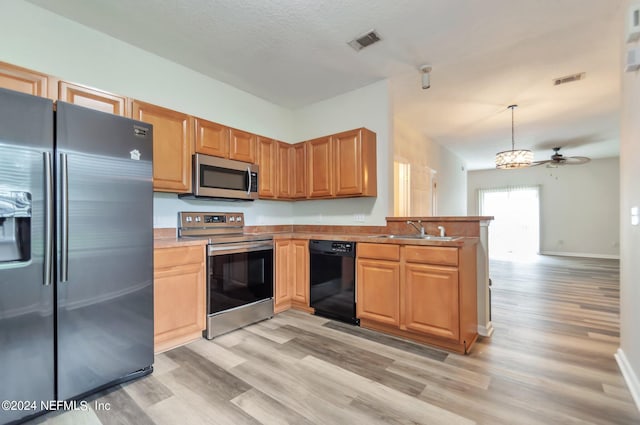 kitchen featuring appliances with stainless steel finishes, light wood-type flooring, ceiling fan, sink, and decorative light fixtures