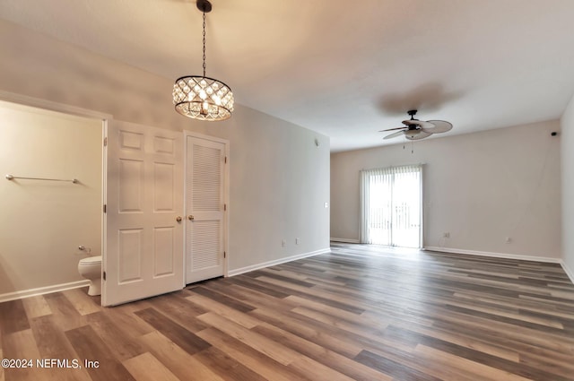 unfurnished room featuring dark wood-type flooring and ceiling fan with notable chandelier