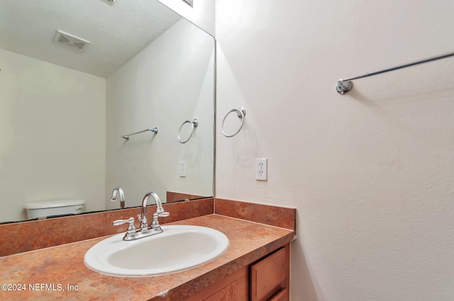 bathroom with vanity, a textured ceiling, and toilet