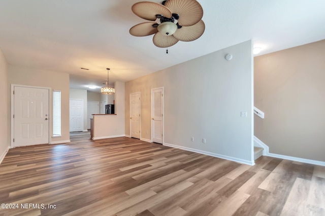 unfurnished living room with hardwood / wood-style flooring and ceiling fan with notable chandelier