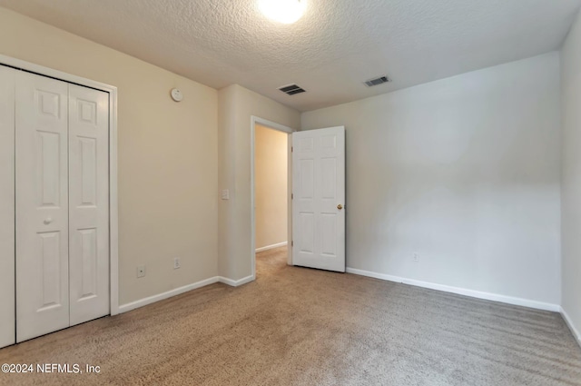 unfurnished bedroom with a closet, carpet floors, and a textured ceiling