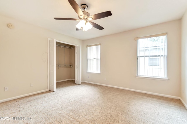 unfurnished bedroom with light carpet, a closet, and ceiling fan