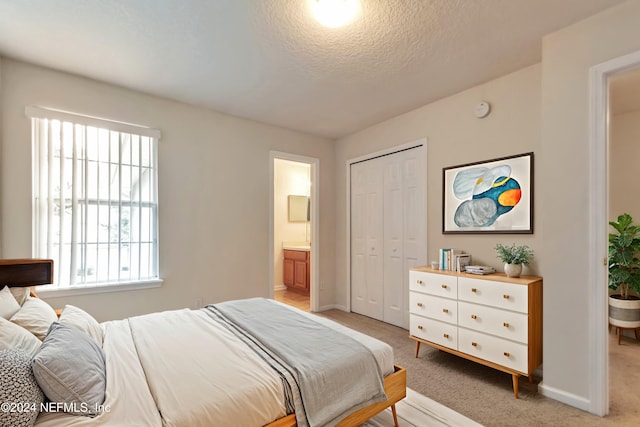 carpeted bedroom with connected bathroom, a closet, and a textured ceiling