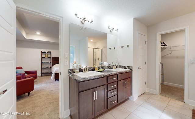 bathroom with tile patterned floors, a textured ceiling, walk in shower, and vanity