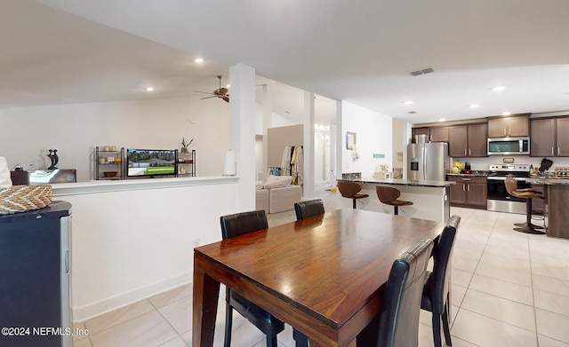 dining room with ceiling fan, light tile patterned floors, and vaulted ceiling