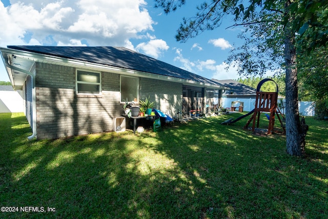 back of house featuring a playground and a yard