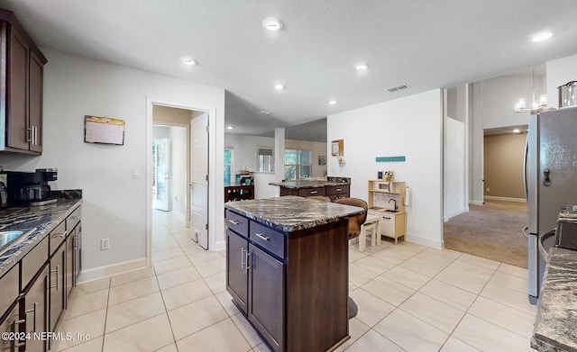 kitchen with dark brown cabinetry, dark stone countertops, and a kitchen island