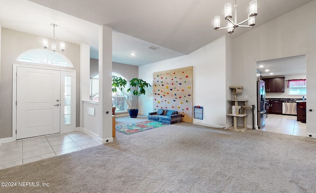 carpeted foyer entrance with a healthy amount of sunlight, a towering ceiling, and a chandelier