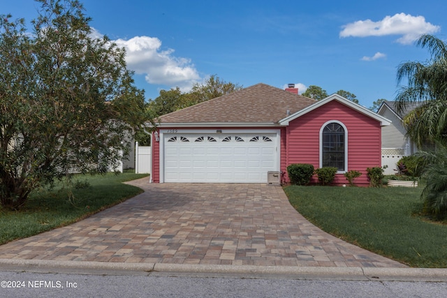 single story home with a garage, a chimney, roof with shingles, decorative driveway, and a front yard