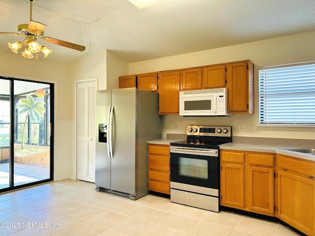 kitchen with stainless steel appliances, light tile patterned floors, a textured ceiling, and a wealth of natural light