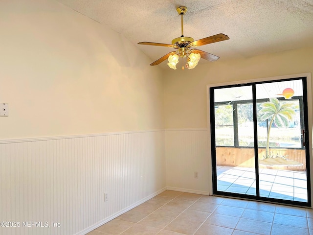 tiled spare room featuring ceiling fan, lofted ceiling, and a textured ceiling