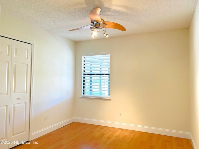 unfurnished room with a ceiling fan, a textured ceiling, baseboards, and wood finished floors