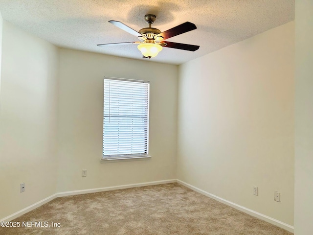 unfurnished room with light carpet, ceiling fan, a textured ceiling, and baseboards