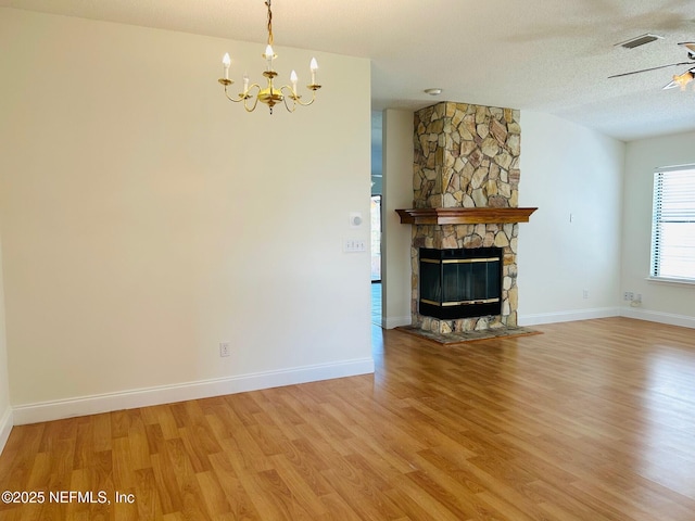 unfurnished living room featuring a fireplace, a textured ceiling, baseboards, and wood finished floors