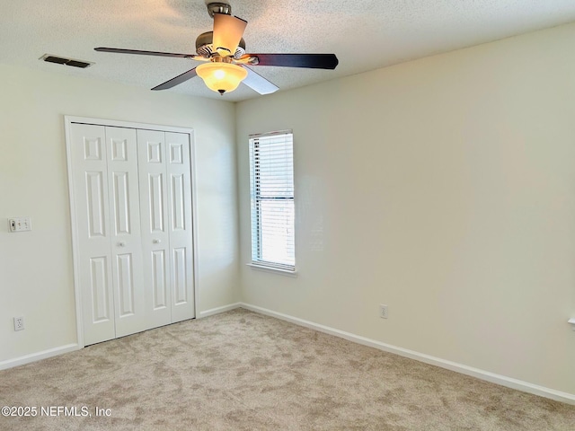 unfurnished bedroom with light carpet, a textured ceiling, a closet, and ceiling fan