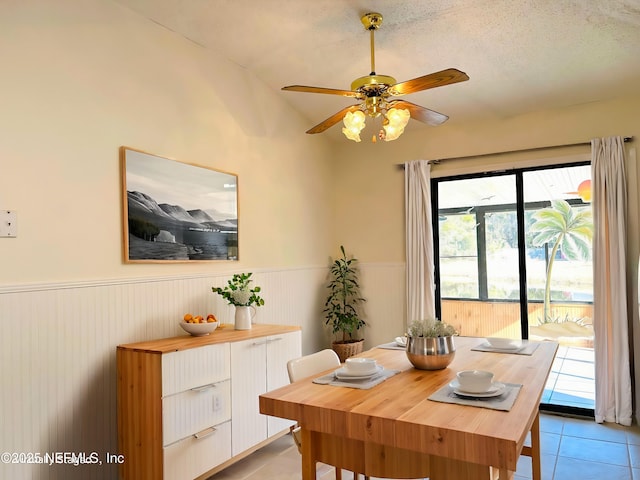 tiled dining area with ceiling fan, lofted ceiling, and a textured ceiling