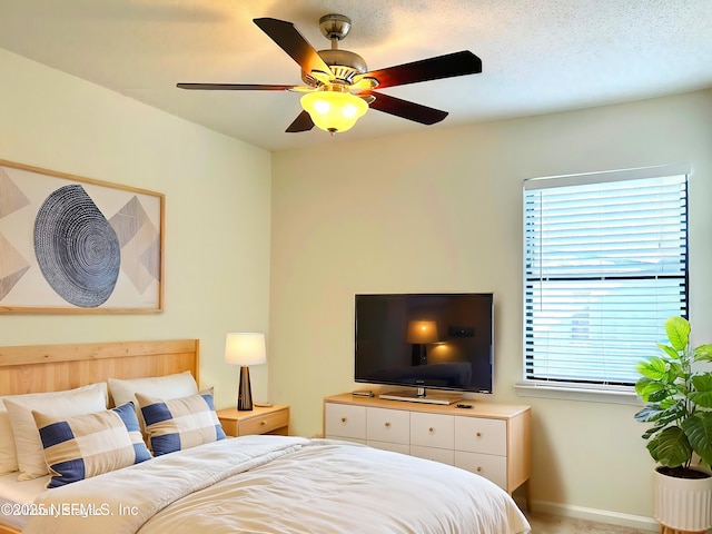 bedroom featuring ceiling fan, baseboards, and a textured ceiling