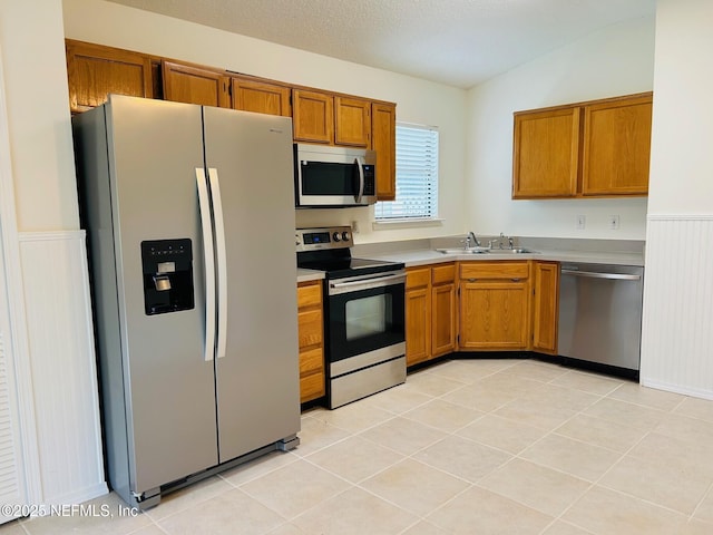 kitchen with stainless steel appliances, brown cabinets, light countertops, and a sink