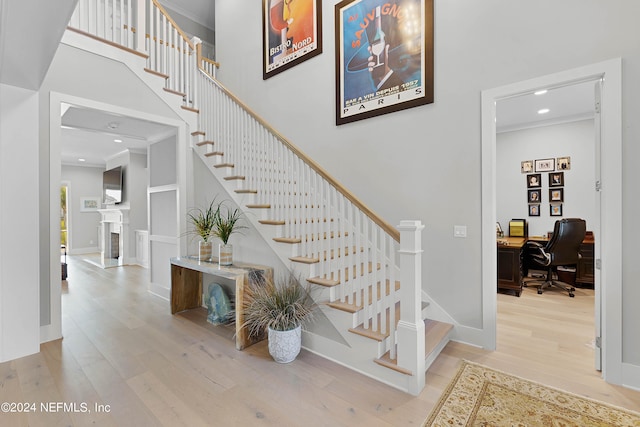 staircase featuring wood-type flooring and crown molding