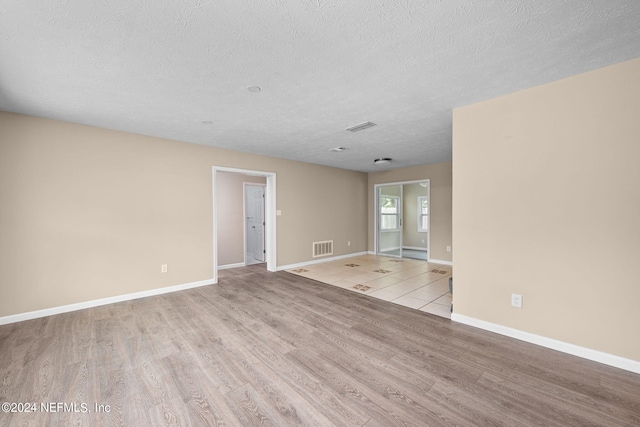 unfurnished room featuring a textured ceiling and light hardwood / wood-style floors