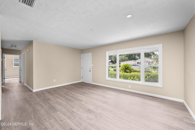 spare room featuring a textured ceiling and light hardwood / wood-style flooring