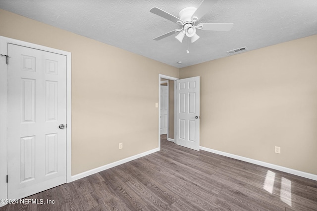 unfurnished bedroom with a textured ceiling, hardwood / wood-style floors, and ceiling fan