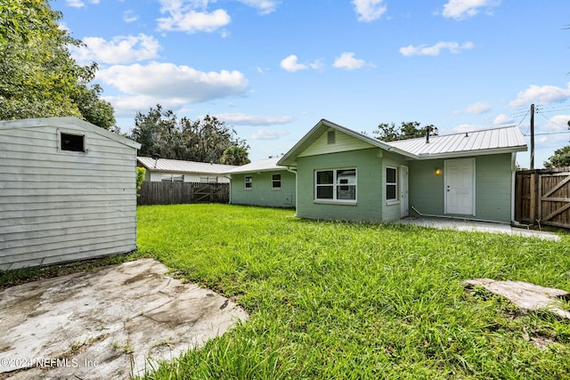 rear view of house with a lawn, a shed, and a patio area